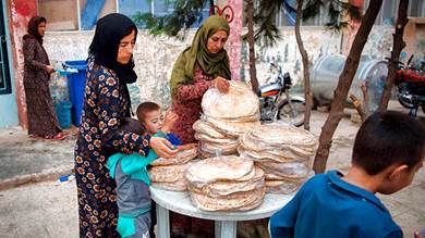 نساء سوريات نازحات يأخذن الخبز، في بلدة الحسكة